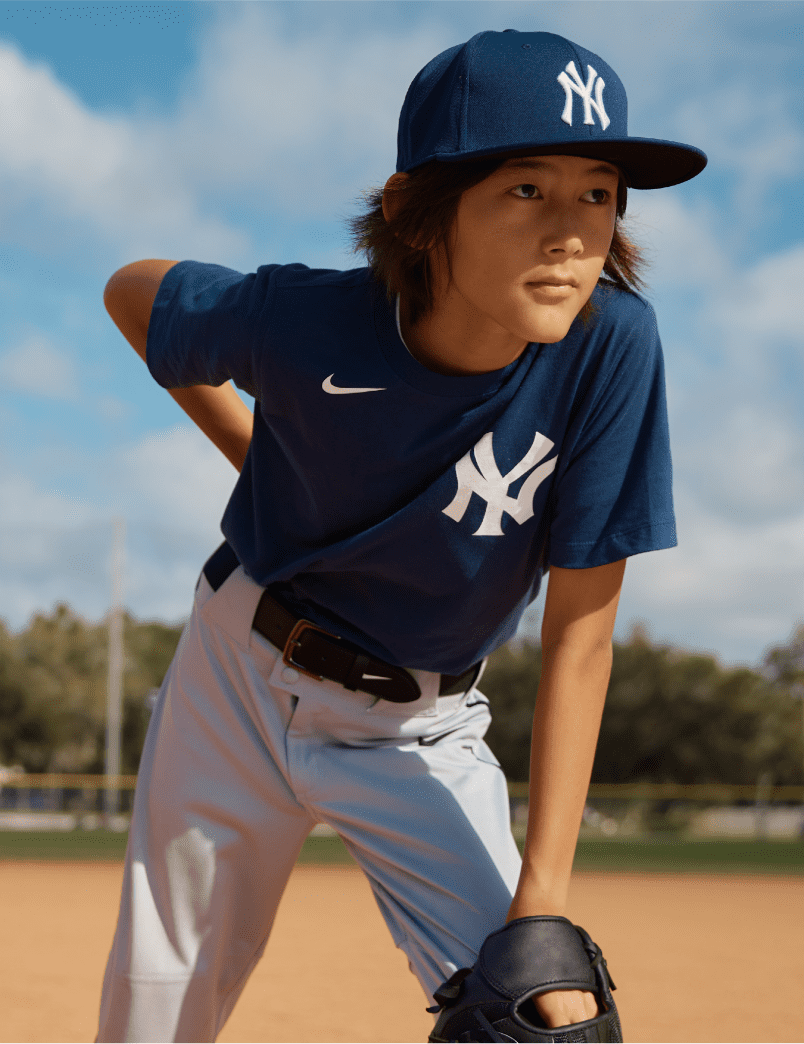 a young pitcher in a navy Yankees baseball jersey and hat with his hand behind his back