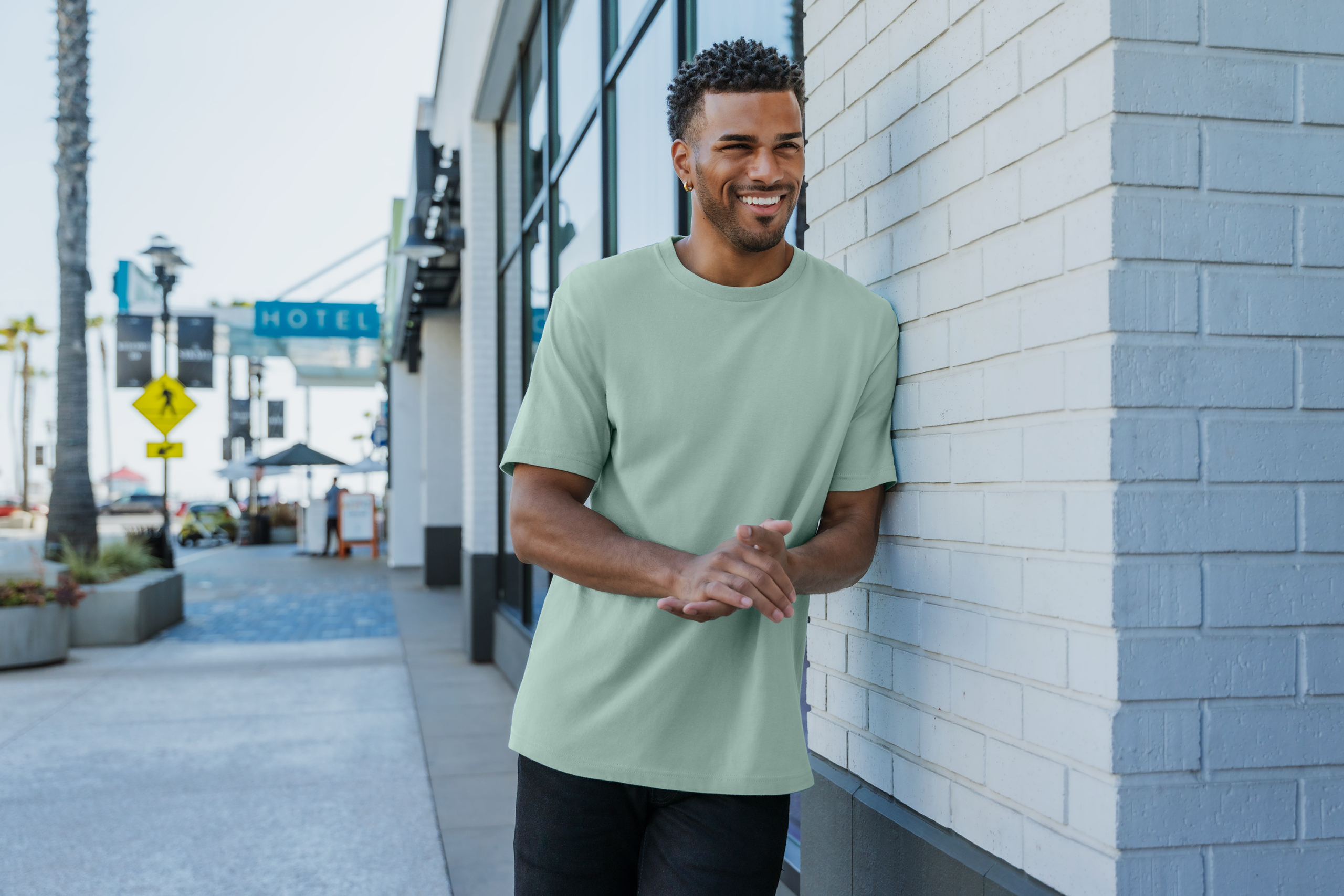a man in a seafoam green shirt smiling and standing against a wall