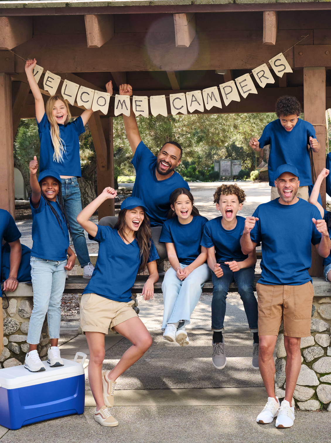 a group of people in royal blue shirts at a campsite raising their fists and doing a pose