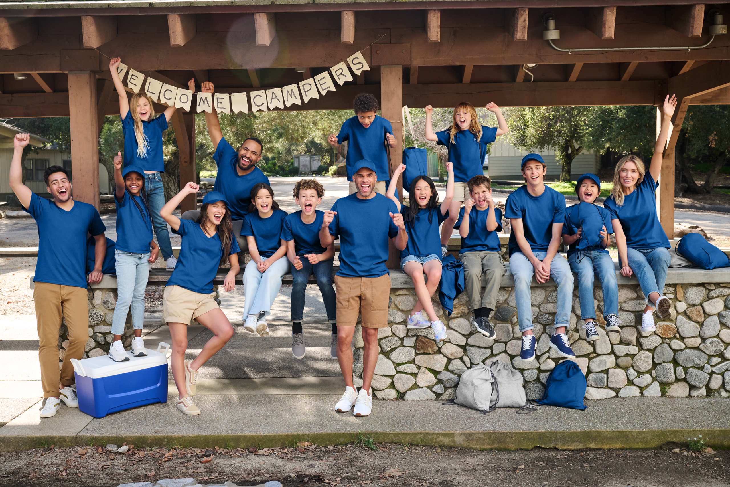 a group of people in royal blue shirts at a campsite raising their fists and doing a pose
